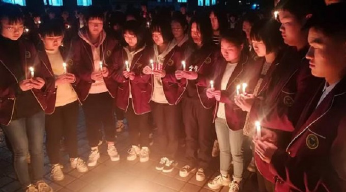 全校学生在教学楼前围成一圈，点燃蜡烛，为牺牲的学长默哀3分钟。