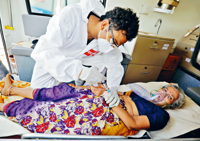 印度艾哈迈达巴德的医生周日在救护车内，救治一名呼吸困难并等候入院的新冠病人。　