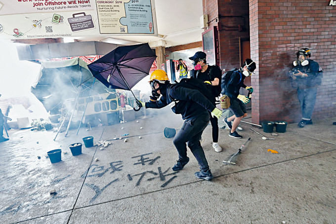 理大事件中，示威者用傘擋催淚彈。