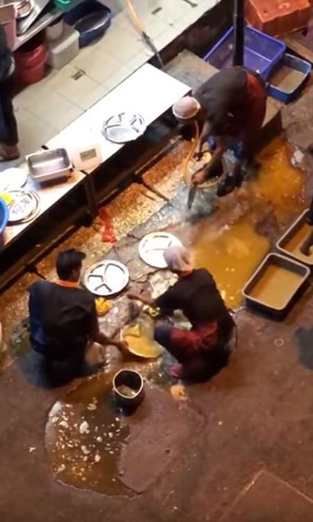4名員工蹲在後巷以路邊黃泥色的積水來洗碗。網圖