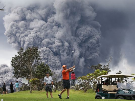 高尔夫球手背向4000尺高的火山灰，若无其事地击球。