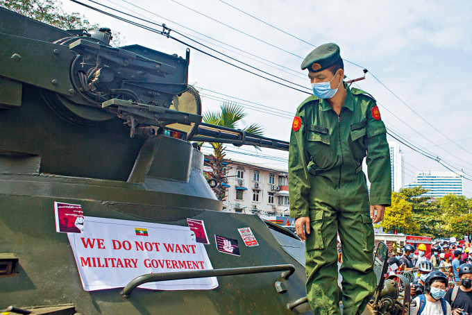 ■仰光市一名士兵昨天看着示威者貼在軍車上「我們不要軍政府」的標語。