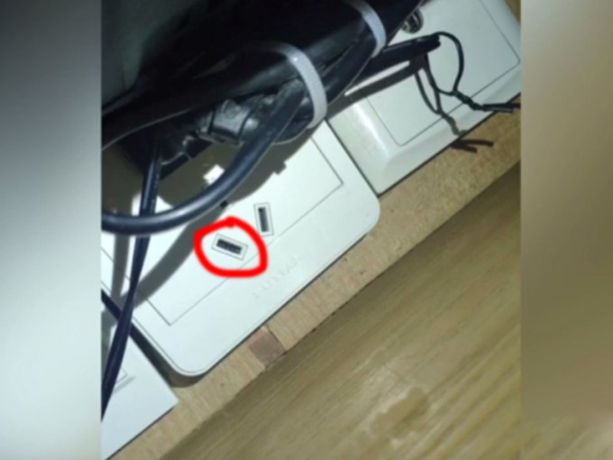 正对睡床的电视机下方一个电插座内，发现藏有一枚镜头。（网图）