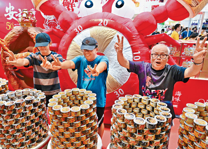 盧先生(右)及兩名隊友在「1蚊搶鮑魚」活動中勝出，獲得500罐即食溏心鮑魚。