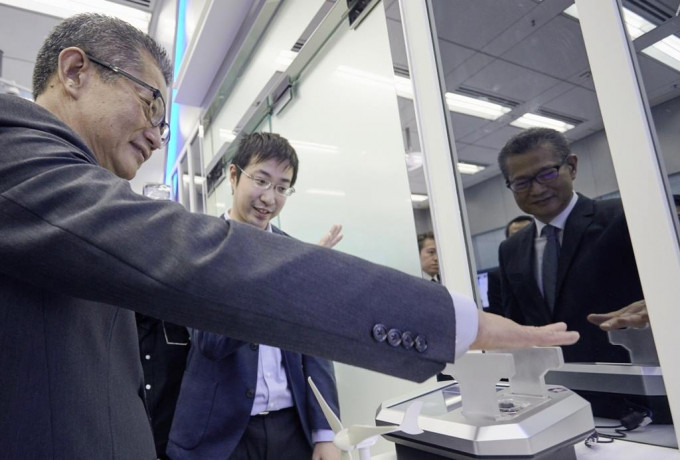 陳茂波（左）參觀香港應用科技研究院時體驗掌紋／掌靜脈混合生物信息認證技術。