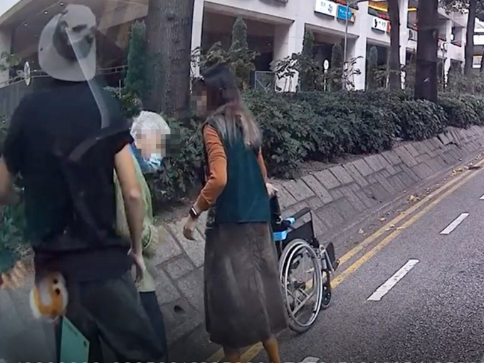 老婦推輪椅誤闖馬路，獲熱心男女護航脫險。影片截圖