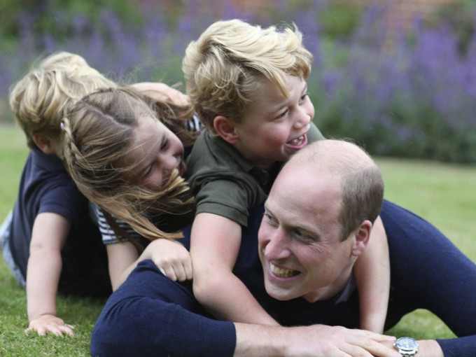威廉與孩子們笑倒在草地上。AP