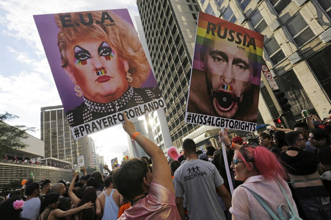 有參加者舉行標語牌，將美國總統特朗普和俄羅斯總統普京描繪成易服皇后。美聯社