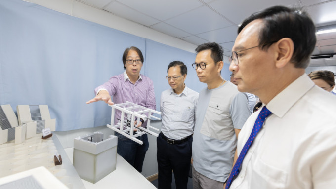 立法会交通事务委员会主席陈恒镔（右二），以及其他立法会议员观看利用三维打印技术制成的「组装合成」升降机结构模型。