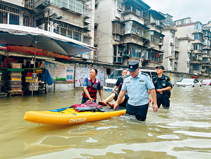 广西钦州暴雨，警察用充气艇救援被困老人。