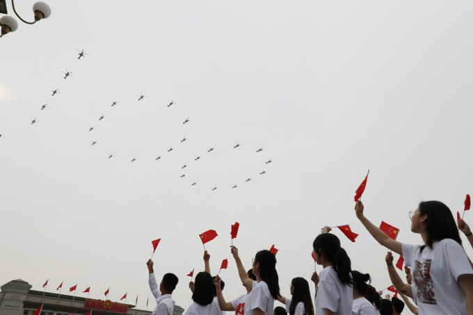 戰機飛越天安門上空，組成「100」、「71」及「人」字形編隊。新華社圖片