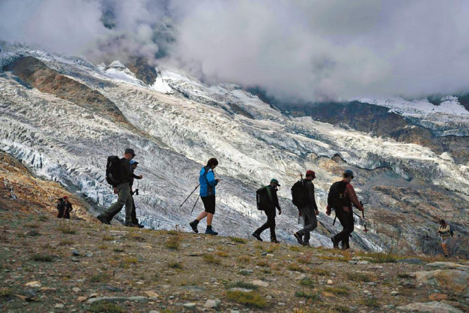 一群登山者上周六步行经过瑞士阿尔卑斯山的一个冰川。