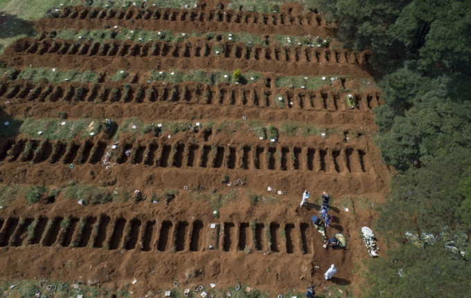 墓地工作人员穿防护服挖新坟，为严峻疫情作准备。AP