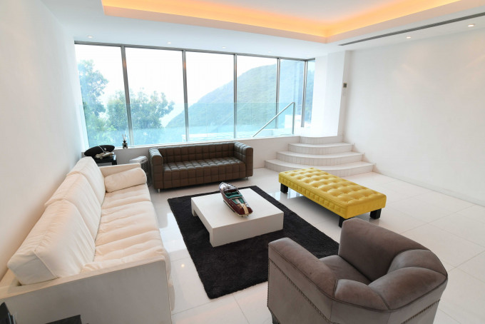 客厅摆放多组大型沙发，亦置黄色长椅，为简约厅堂增添点缀。