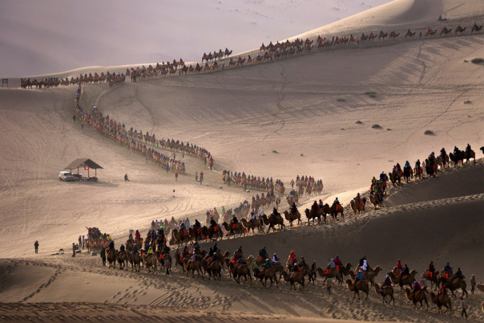敦煌鳴沙山月牙泉景區遊客排出駱駝陣。新華社