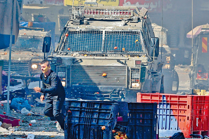 在西岸納布盧斯市，巴人周三跑避以色列軍車。