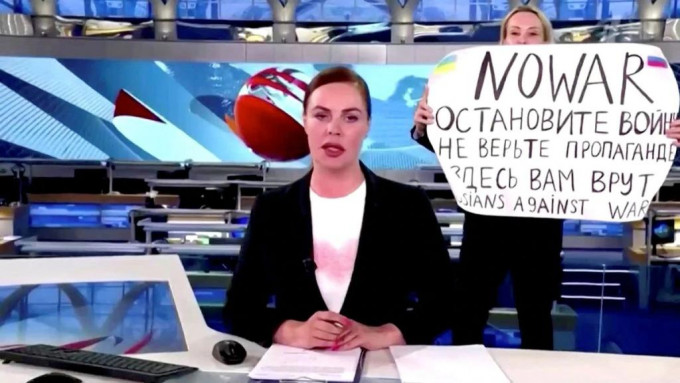 奥夫相妮科娃在新闻节目直播期间，站在后方举起标语。互联网图片