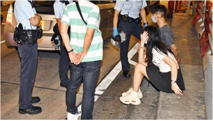 被捕的34岁男司机及29岁女乘客坐于石壆上。