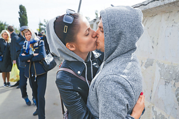 俄羅斯伏爾加格勒一名奉召入伍的男子，與妻子相擁吻別。
