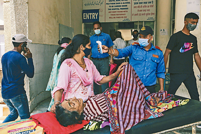 印度查谟一名陪诊女子，周一进入政府医院前检查体温。