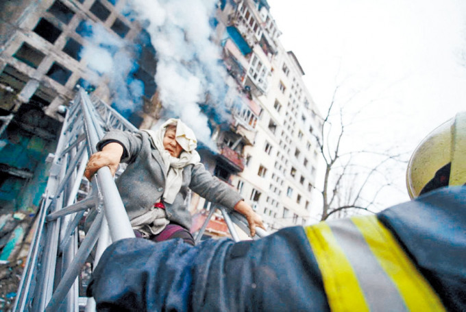 救援人员在基辅被炮轰的住宅大楼，救出一名妇女。