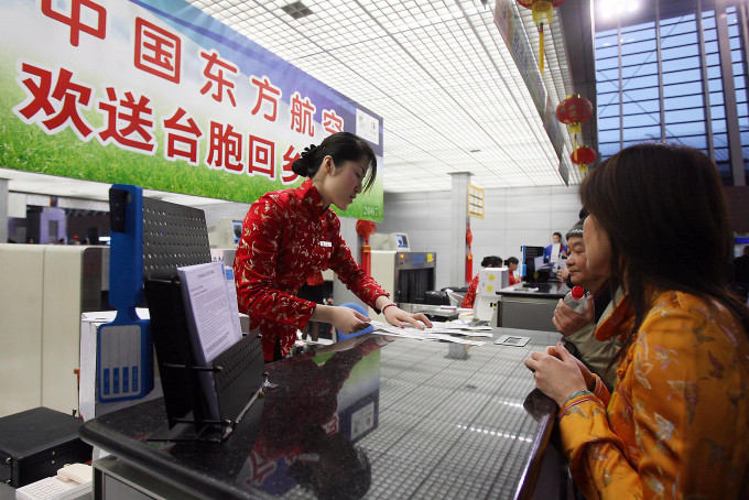 旅客在浦东机场东航柜台办理两岸春节包机登机手续。