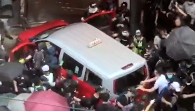 当时的士被示威人群包围，其后司机被打伤。