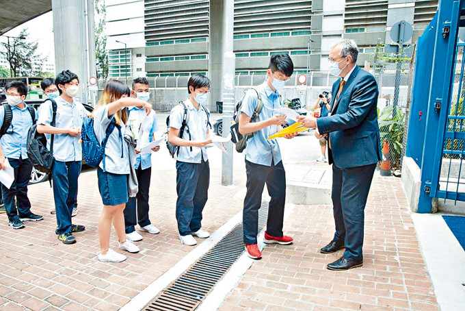 宣道国际学校学生昨抵校时要交健康申报表，校长温德培在门口迎接学生。