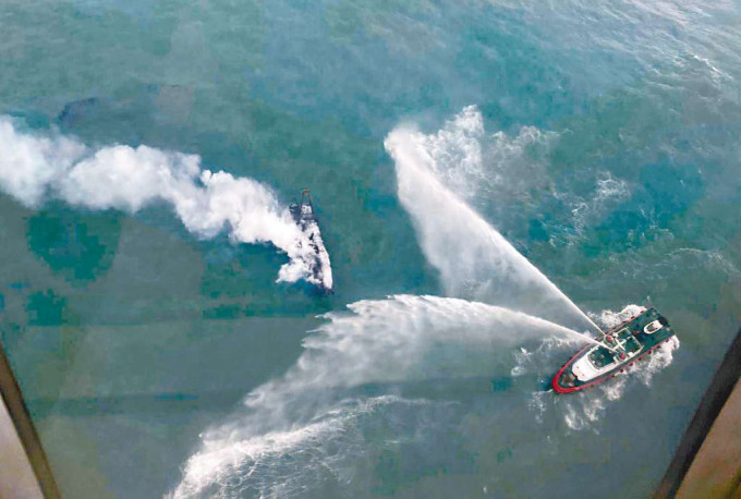 ■起火漁船冒出濃煙，在旁消防輪射水灌救。