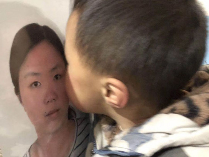 儿子葬礼中亲吻妈妈的遗照。(网图)