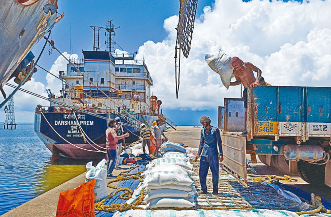在印度安德拉邦卡基納達港口，貨運工人準備將大米運上貨輪。