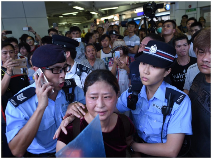 中年女子在警方護送下上警車。