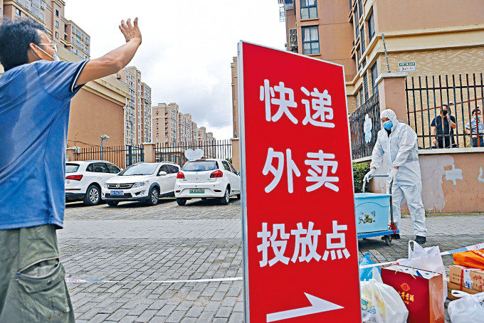 上海浦东心圆西苑小区被封，外卖员在门口交收。社区团购疫境大旺，学者料今年规模超过一千亿元。