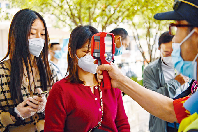 鐵路人員為進入武漢站的旅客測溫。