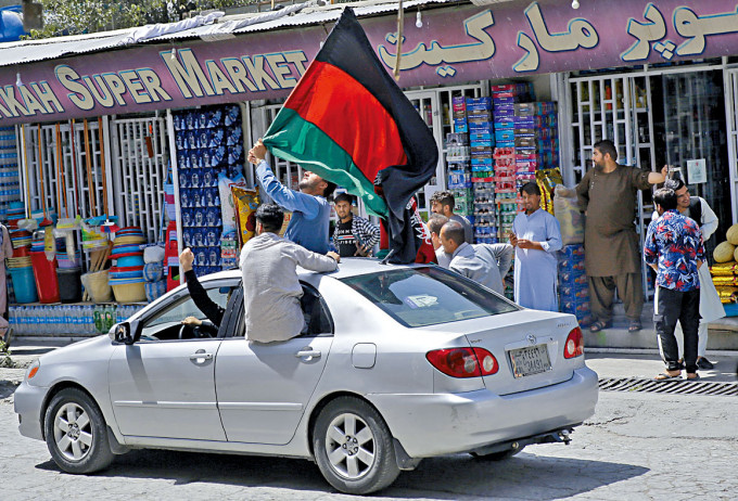喀布尔街头昨日有人乘汽车挥舞黑、红、绿三色的阿富汗旗帜。