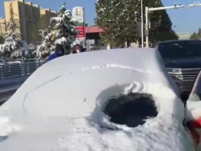 积雪覆盖车窗女子仅清理一小洞驾驶。