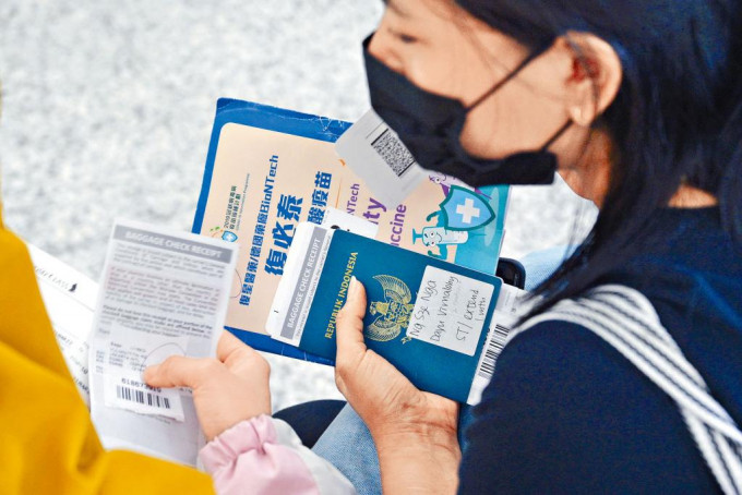 手持印尼护照女子亦持有复必泰小册子。
