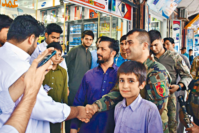 ■阿富汗南部年轻将领萨达特（右），与民众握手。