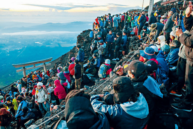 大批游客涌到富士山顶观看日出。