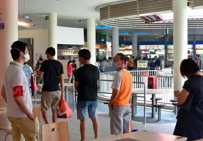 新加坡市民保持距离排队买饭。AP