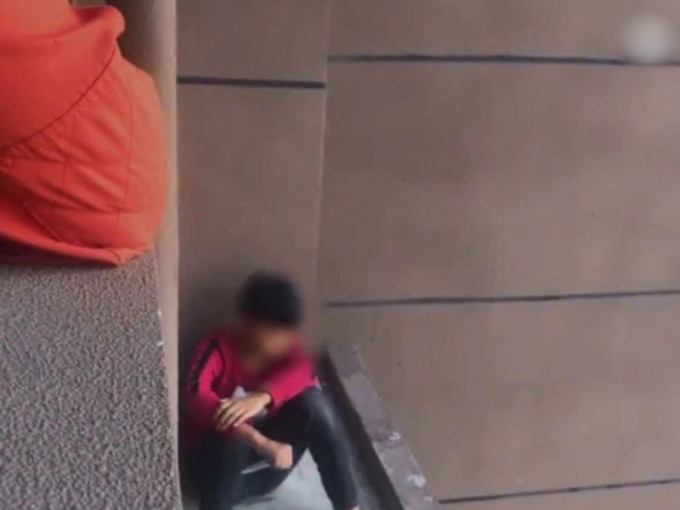 男童手持水果刀坐在一大樓27樓邊緣，想藉此了結自己的性命。 影片截圖