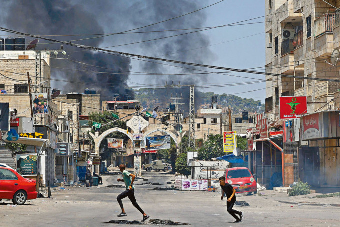 以军周一向西岸杰宁市展开大规模攻击行动，巴勒斯坦年轻人奔走躲避。　