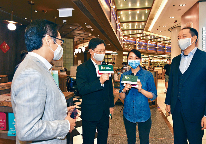 ■创科局局长薛永恒(左二)昨到荃湾区，听取茶餐厅店长讲述应用「安心出行」的好处。