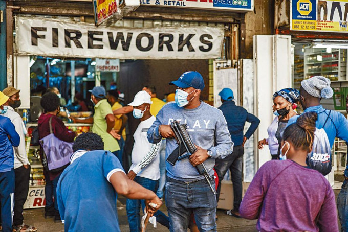 ■南非约翰内斯堡市民周四排队购烟花准备庆祝新年，一名便衣警察在场维持秩序。