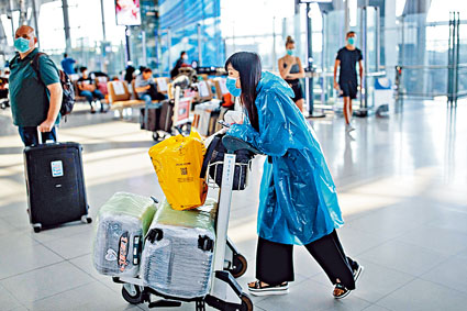 曼谷國際機場昨日有旅客戴口罩兼穿塑膠保護衣防疫。