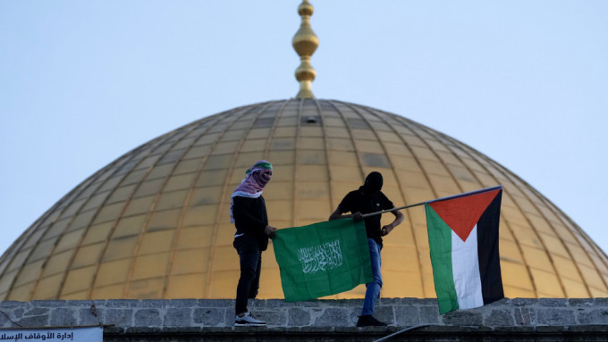 巴勒斯坦人在開齋節慶祝活動中，在圓頂清真寺旁舉着哈馬斯旗和巴勒斯坦國旗。 美聯社