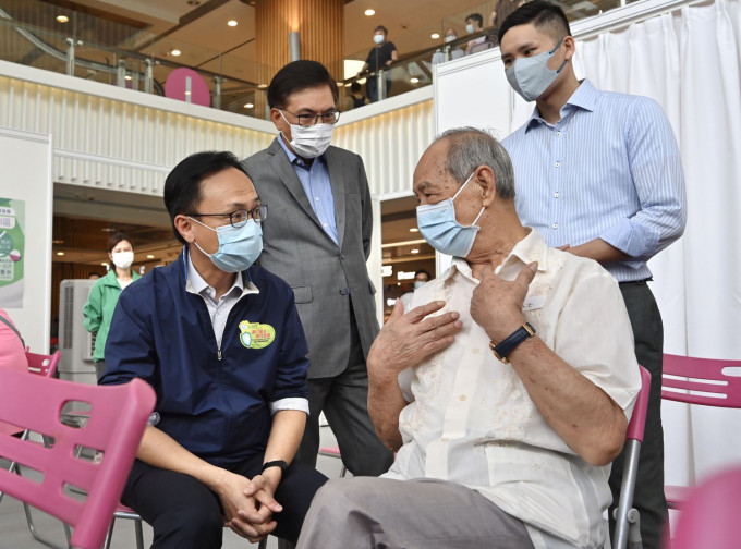 聂德权（前排左）与一名参与疫苗接种活动的长者交谈。政府新闻处图片