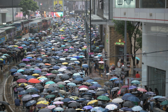 大批示威者撑起伞冒雨游行。