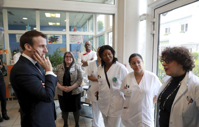 法国总统马克龙向医护人员了解抗疫情况。AP