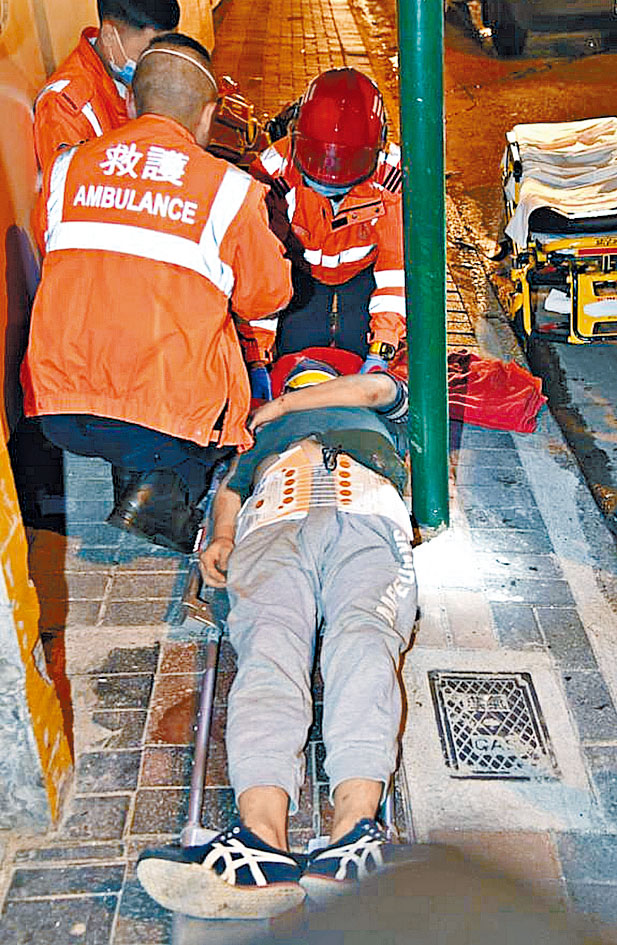 救护员替被撞伤倒地男子包扎。